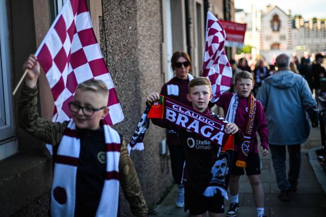 Young Hearts fans hold flags and banners as they arrive before the start of the Scottish Premiership football match between Hearts and Rangers at Tynecastle Stadium in Edinburgh on May 4, 2026. Hearts are hoping to become the first club other than Celtic and Rangers to win the Scottish crown since Aberdeen in 1985. (Photo by ANDY BUCHANAN / AFP)