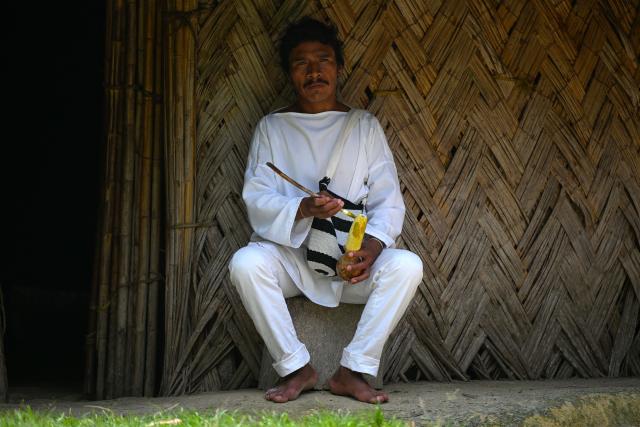 A Kogui Indigenous person crafts a poporo — a traditional gourd used by Indigenous peoples to mix coca leaves with lime — while chewing coca leaves in Palmor, Magdalena department, Colombia, on April 17, 2026. At first glance, it appears to be a postcard-perfect tourist jewel, with crystal-clear Caribbean waters and mountains crowned by snowcapped peaks. But beneath the surface of Colombias idyllic destination, paramilitary violence keeps shopkeepers and Indigenous communities living in fear. In the Sierra Nevada de Santa Marta, tourists roam unaware of camouflaged squads monitoring them from close range, extorting nearby businesses and spreading terror among Indigenous communities, whose ancestral knowledge has been recognized by UNESCO as part of the worlds cultural heritage. (Photo by Luis ACOSTA / AFP)