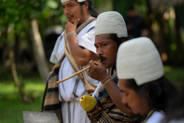 Arhuaco Indigenous men chew coca leaves at the Kutunsama Indigenous Reservation in Tayrona National Natural Park, Magdalena department, Colombia, on April 18, 2026. At first glance, it appears to be a postcard-perfect tourist jewel, with crystal-clear Caribbean waters and mountains crowned by snowcapped peaks. But beneath the surface of Colombias idyllic destination, paramilitary violence keeps shopkeepers and Indigenous communities living in fear. In the Sierra Nevada de Santa Marta, tourists roam unaware of camouflaged squads monitoring them from close range, extorting nearby businesses and spreading terror among Indigenous communities, whose ancestral knowledge has been recognized by UNESCO as part of the worlds cultural heritage. (Photo by Luis ACOSTA / AFP)