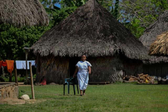 An Arhuaco Indigenous woman walks at the Kutunsama Indigenous Reservation in Tayrona National Natural Park, Magdalena department, Colombia, on April 18, 2026. At first glance, it appears to be a postcard-perfect tourist jewel, with crystal-clear Caribbean waters and mountains crowned by snowcapped peaks. But beneath the surface of Colombias idyllic destination, paramilitary violence keeps shopkeepers and Indigenous communities living in fear. In the Sierra Nevada de Santa Marta, tourists roam unaware of camouflaged squads monitoring them from close range, extorting nearby businesses and spreading terror among Indigenous communities, whose ancestral knowledge has been recognized by UNESCO as part of the worlds cultural heritage. (Photo by Luis ACOSTA / AFP)