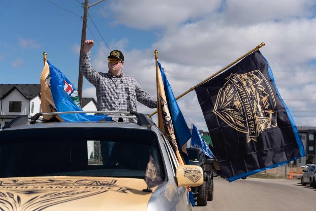 A separatist supporter waves a flag during as part of a convoy in Edmonton, Canada, on May 4, 2026, as they submit boxes of signatures in the hope of triggering an independence referendum. Alberta separatists submitted stacks of boxes to election officials on Monday, which they said contained the signatures of more than 300,000 supporters, enough names to force an independence referendum in Canada's oil-rich province. A boisterous crowd of several hundred waved the blue provincial flag on a bright, clear day, cheering as separatist leader Mitch Sylvestre delivered the petitions to Elections Alberta. (Photo by Henry MARKEN / AFP)