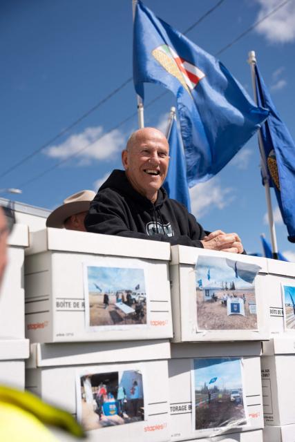 Separatist leader Mitch Sylvestre is seen during a rally in front of the Elections Alberta headquarters in Edmonton, Canada, on May 4, 2026, as they submit boxes of signatures in the hope of triggering an independence referendum. Alberta separatists submitted stacks of boxes to election officials on Monday, which they said contained the signatures of more than 300,000 supporters, enough names to force an independence referendum in Canada's oil-rich province. A boisterous crowd of several hundred waved the blue provincial flag on a bright, clear day, cheering as separatist leader Mitch Sylvestre delivered the petitions to Elections Alberta. (Photo by Henry MARKEN / AFP)