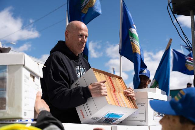 Separatist leader Mitch Sylvestre is seen during a rally in front of the Elections Alberta headquarters in Edmonton, Canada, on May 4, 2026, as they submit boxes of signatures in the hope of triggering an independence referendum. Alberta separatists submitted stacks of boxes to election officials on Monday, which they said contained the signatures of more than 300,000 supporters, enough names to force an independence referendum in Canada's oil-rich province. A boisterous crowd of several hundred waved the blue provincial flag on a bright, clear day, cheering as separatist leader Mitch Sylvestre delivered the petitions to Elections Alberta. (Photo by Henry MARKEN / AFP)