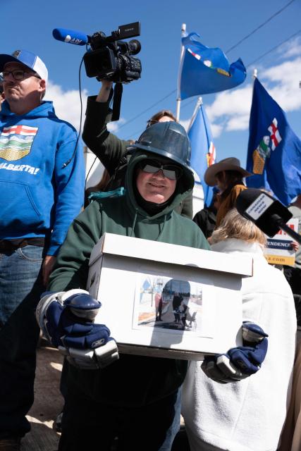 A separatist supporter holds a box during a rally in front of the Elections Alberta headquarters in Edmonton, Canada, on May 4, 2026, as they submit boxes of signatures in the hope of triggering an independence referendum. Alberta separatists submitted stacks of boxes to election officials on Monday, which they said contained the signatures of more than 300,000 supporters, enough names to force an independence referendum in Canada's oil-rich province. A boisterous crowd of several hundred waved the blue provincial flag on a bright, clear day, cheering as separatist leader Mitch Sylvestre delivered the petitions to Elections Alberta. (Photo by Henry MARKEN / AFP)