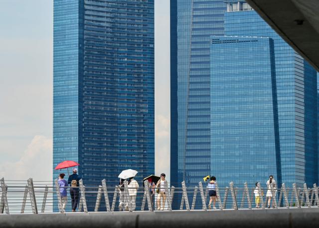 People walk across Jubilee bridge at Marina Bay in Singapore on May 5, 2026. (Photo by Roslan RAHMAN / AFP)