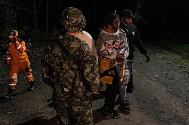Relatives mourn the death of nine miners past a Colombian soldier after an explosion at a coal mine in Sutatausa, Cundinamarca department, Colombia on May 4, 2026. Nine miners died and six others were rescued following an explosion at a legal coal mine in central Colombia on May 4, 2026, according to the final tally released by authorities at the end of the search operation. (Photo by Luis ACOSTA / AFP)