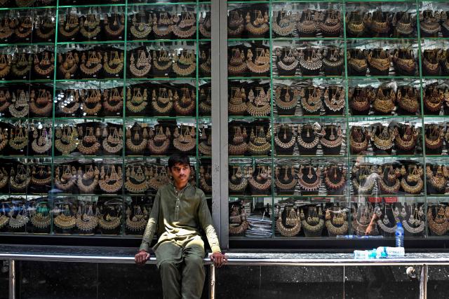 A daily wage labourer sits outside a jewellery shop in Lahore on May 5, 2026. (Photo by Arif ALI / AFP)
