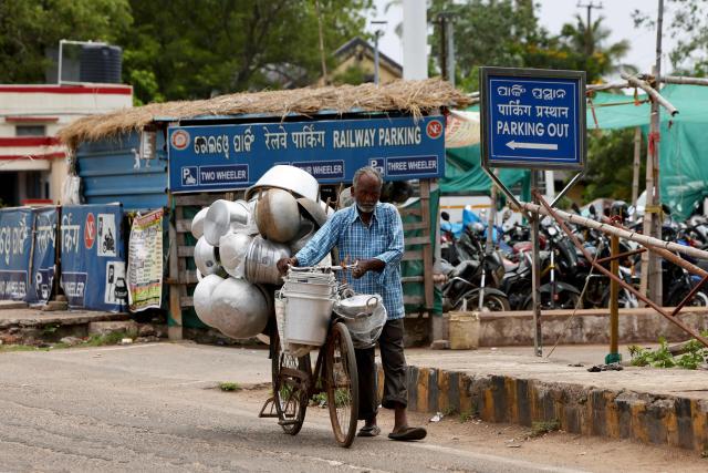 A man transports aluminium containers on a bicycle along a street on a hot summer day in Bhubaneswar on May 5, 2026. (Photo by Niharika KULKARNI / AFP)