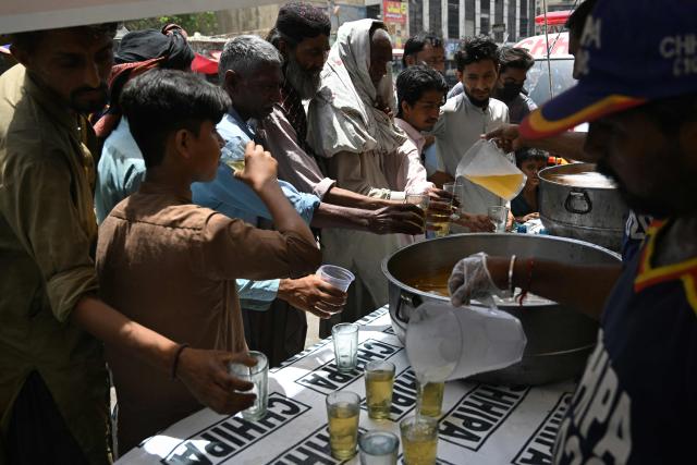 Volunteers distribute chilled refreshments to commuters along a street on a hot summer day in Karachi on May 5, 2026. (Photo by Rizwan TABASSUM / AFP)