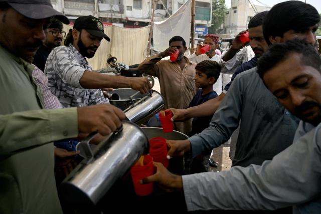 Volunteers distribute chilled refreshments to commuters along a street on a hot summer day in Karachi on May 5, 2026. (Photo by Rizwan TABASSUM / AFP)