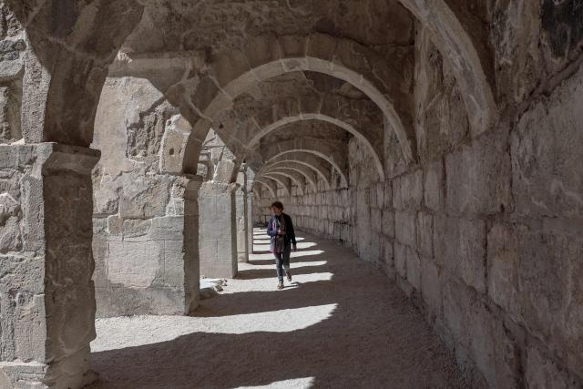 A tourist walks under the arcades during a visit at the ancient amphitheater of Aspendos, part of the ancient Greco-Roman city in Antalya province, in Antalya on May 4, 2026. (Photo by Adem ALTAN / AFP)