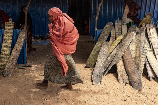 An internally displaced girl attend a lesson in Madrasa to read Koranic verses engraved on pieces of wood in a camp for displaced people in the outskirts of Kismayo town, on April 21, 2026. Millions of people in Somalia are facing the repercussions of a severe drought after three consecutive failed raining seasons. Kismayo, the capital of Jubaland State in southern Somalia, is one of the largest IDP-receiving cities in the Horn of Africa country, receiving hundreds of thousands of people fleeing the prolonged drought and conflict. Save the Children provides health and nutrition services across the camp. (Photo by SIMON MAINA / AFP)