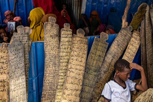 Internally displaced boy resting after attending a lesson in Madrasa to read and write Koranic verses engraved on pieces of wood in a camp for displaced people in the outskirts of Kismayo town, on April 21, 2026. Millions of people in Somalia are facing the repercussions of a severe drought after three consecutive failed raining seasons. Kismayo, the capital of Jubaland State in southern Somalia, is one of the largest IDP-receiving cities in the Horn of Africa country, receiving hundreds of thousands of people fleeing the prolonged drought and conflict. Save the Children provides health and nutrition services across the camp. (Photo by SIMON MAINA / AFP)