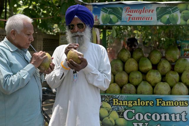 Men drink coconut water on a hot summer day along a street in Amritsar on May 5, 2026. (Photo by Narinder NANU / AFP)