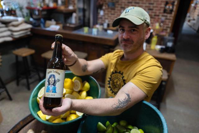 French brewer Aurelien Picard holds a bottle of a beer named 'John Lemon', a play on words in reference to British musician John Lennon at the brewery 'Brasserie de l'imprimerie' in Bannalec, western France on May 5, 2026. Following a formal notice from Yoko Ono, the widow of the Beatles singer, a Breton brewery has sold several thousand bottles of ‘John Lemon’ beer in just a few days – beer it will no longer be able to sell after July 1, 2026, the brewer told AFP on May 5, 2026. At the end of March, a Dutch law firm served the brewery with a formal notice to cease marketing ‘John Lemon’, failing which it would face having to pay substantial sums to the Yoko Ono Trust, which is responsible for protecting John Lennon’s image. (Photo by Fred TANNEAU / AFP)