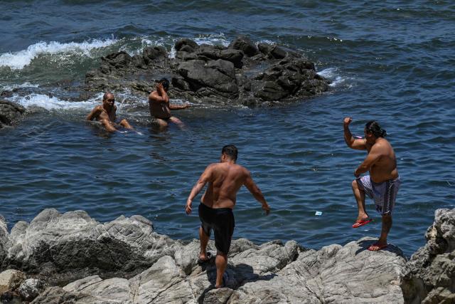 Men take a dip in the sea by a rocky coastline in Santa, Ilocos Sur on May 5, 2026. (Photo by Jam STA ROSA / AFP)