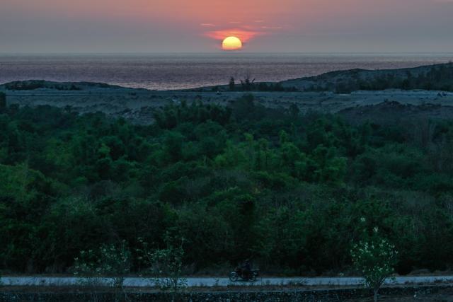 A motorcyclist (foreground) passes by as the sun sets in Paoay, Ilocos Norte on May 5, 2026. (Photo by JAM STA ROSA / AFP)