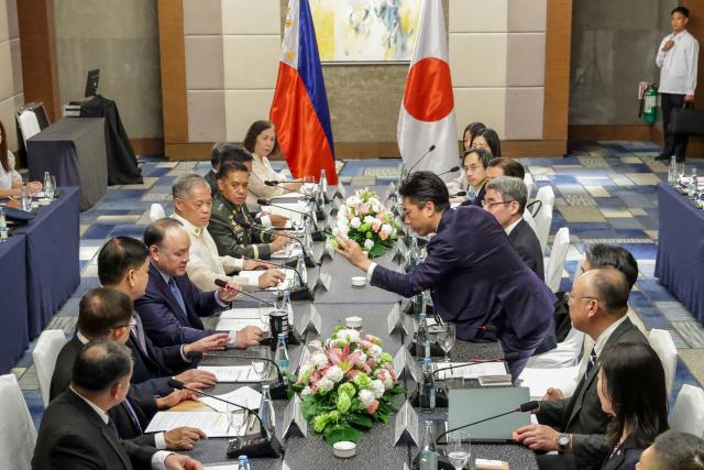 Japan's Defense Minister Shinjiro Koizumi (centre R) stands up to check the microphone of Philippines' Defense Secretary Gilbert Teodoro Jr. (centre L) during a bilateral meeting in Manila on May 5, 2026.  (Photo by MARK CRISTINO / AFP)
