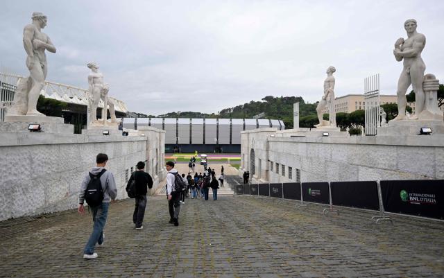 People walk near the "Super Tennis Arena" a temporary tennis court built inside the Marble Stadium (Stadio dei Marmi) for the ATP/WTA Tennis tournament of Rome, on May 5, 2026. (Photo by Tiziana FABI / AFP)