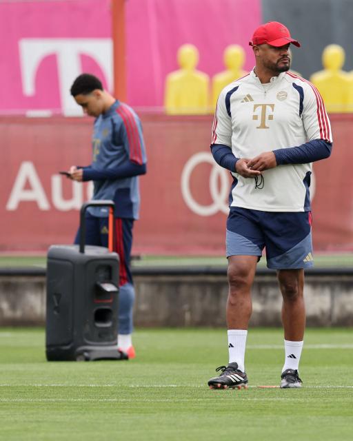 Bayern Munich's Belgian head coach Vincent Kompany (front R) walks across the pitch while Bayern Munich's German midfielder #10 Jamal Musiala in the background stands next to a sound system during a training session of FC Bayern Munich at their training ground in the Saebener Strasse in Munich, southern Germany on May 5, 2026, the eve of the UEFA Champions League second-leg semi-final football match against Paris Saint-Germain (PSG). (Photo by Alexandra BEIER / AFP)