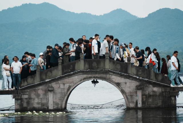 People crowd a bridge over West Lake in Hangzhou, in China’s eastern Zhejiang province on May 3, 2026, during a five-day national May Day holiday. (Photo by CN-STR / AFP) / China OUT