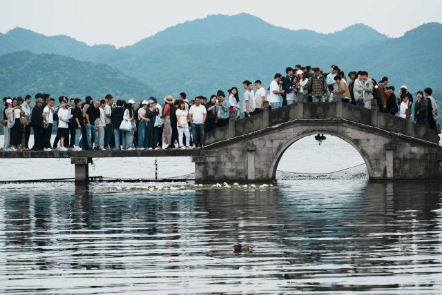People crowd a walkway and bridge over West Lake in Hangzhou, in China’s eastern Zhejiang province on May 3, 2026, during a five-day national May Day holiday. (Photo by CN-STR / AFP) / China OUT