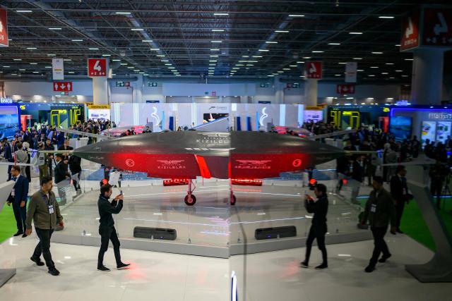 Visitors look at a Bayraktar KIZILELMA Unmanned Combat Aircraft (UCAV), developed by Turkey's defence company Baykar on a stand during the opening day of the SAHA EXPO 2024, an International Defence and Aerospace exhibition, in Istanbul on May 5, 2026. (Photo by Yasin AKGUL / AFP)