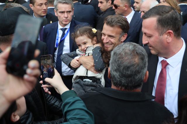France's President Emmanuel Macron holds a girl surrounded by the crowd in Gyumri on May 5, 2026. (Photo by Ludovic MARIN / AFP)