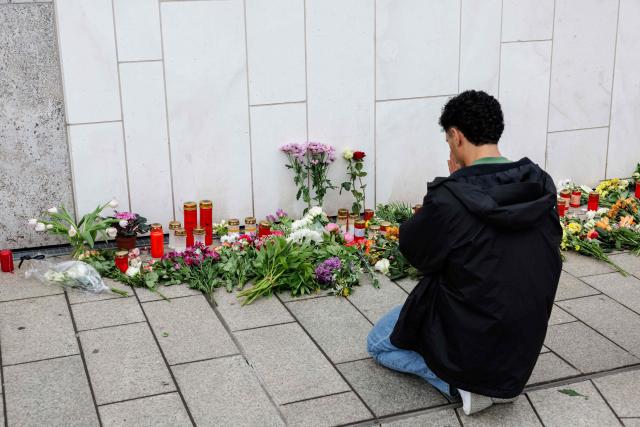 A man reacts at a makeshift memorial of flowers and candles placed in front of the Paulinum (University Auditorium and St Pauli University Church) in Leipzig, eastern Germany, on May 5, 2026, close to the site where a car ploughed into people on a street, leaving at least two dead and several injured, one day after the incident. A man suspected of ploughing a car into a crowd in the eastern German city of Leipzig, killing two people, recently underwent treatment in a psychiatric hospital, the authorities said on May 5. The German national allegedly drove the vehicle on May 4 at high speed down a main street in the historic centre of the eastern city, leaving two people dead and many others wounded. The 33-year-old suspect was arrested at the scene and officials have said they do not believe he had a political or religious motive. (Photo by Jens SCHLÜTER / AFP)