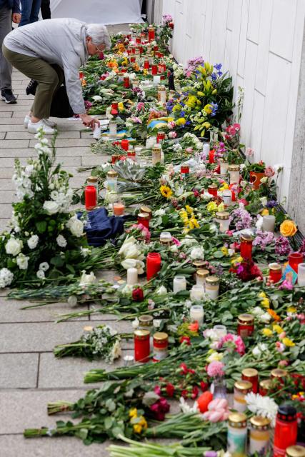A woman lights a candle at a makeshift memorial in front of the Paulinum (University Auditorium and St Pauli University Church) in Leipzig, eastern Germany, on May 5, 2026, close to the site where a car ploughed into people on a street, leaving at least two dead and several injured, one day after the incident. A man suspected of ploughing a car into a crowd in the eastern German city of Leipzig, killing two people, recently underwent treatment in a psychiatric hospital, the authorities said on May 5. The German national allegedly drove the vehicle on May 4 at high speed down a main street in the historic centre of the eastern city, leaving two people dead and many others wounded. The 33-year-old suspect was arrested at the scene and officials have said they do not believe he had a political or religious motive. (Photo by Jens SCHLÜTER / AFP)
