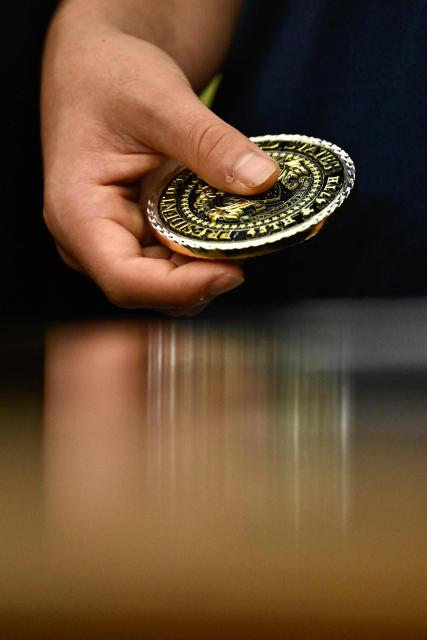 A student holds a presidential challenge coin as US President Donald Trump speaks before signing a proclamation to revive the Presidential Fitness Test Award, a competitive school-based fitness program, in the Oval Office of the White House in Washington, DC on May 5, 2026. (Photo by Kent NISHIMURA / AFP)