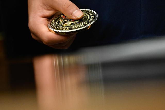 A student holds a presidential challenge coin as US President Donald Trump speaks before signing a proclamation to revive the Presidential Fitness Test Award, a competitive school-based fitness program, in the Oval Office of the White House in Washington, DC on May 5, 2026. (Photo by Kent NISHIMURA / AFP)
