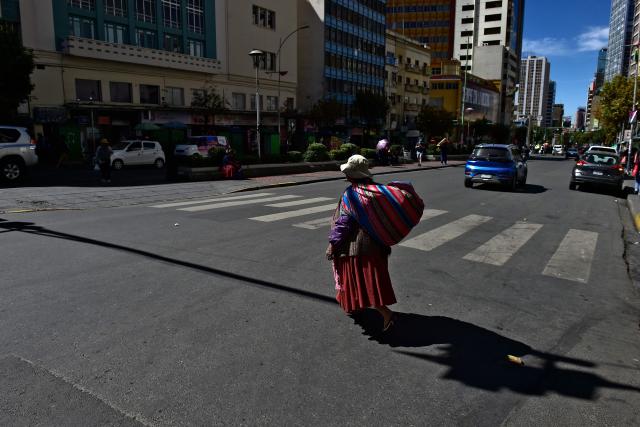 An Indigenous woman crosses an almost empty street during a 24-hour transport strike called by the Bolivian Drivers’ Confederation in protest for the bad quality of oil, in La Paz on May 5, 2026. Drivers demand financial compensation from the government for the damage caused to their vehicles. (Photo by Jorge BERNAL / AFP)