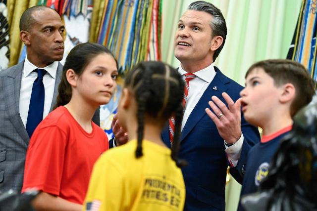 (L/R) US Secretary of Housing and Urban Development Scott Turner and students look on as US Secretary of Defense Pete Hegseth speaks before President Donald Trump signs a proclamation to revive the Presidential Fitness Test Award, a competitive school-based fitness program, in the Oval Office of the White House in Washington, DC on May 5, 2026. (Photo by Kent NISHIMURA / AFP)