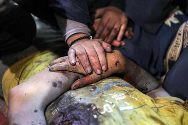 EDITORS NOTE: Graphic content / A woman mourns over the body of Palestinian child Mahmoud Sahwil, 14, who was killed during an Israeli strike on a police station in the Sheikh Radwan neighbourhood, as the body lies at the morgue at Shifa Hospital in Gaza City on May 5, 2026. (Photo by Omar AL-QATTAA / AFP)