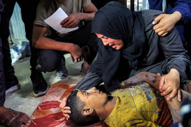 EDITORS NOTE: Graphic content / A woman mourns over the body of Palestinian child Mahmoud Sahwil, 14, who was killed during an Israeli strike on a police station in the Sheikh Radwan neighbourhood, as the body lies at the morgue at Shifa Hospital in Gaza City on May 5, 2026. (Photo by Omar AL-QATTAA / AFP)