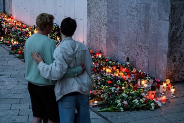 People pay their respects with flowers and candles at a makeshift memorial in front of the Paulinum (University Auditorium and St Pauli University Church) in Leipzig, eastern Germany, close to the site where a car ploughed into people on a street, leaving at least two dead and several injured, one day after the incident, on May 5, 2026. A man suspected of ploughing a car into a crowd in the eastern German city of Leipzig, killing two people, recently underwent treatment in a psychiatric hospital, the authorities said on May 5. The German national allegedly drove the vehicle on May 4 at high speed down a main street in the historic centre of the eastern city, leaving two people dead and many others wounded. The 33-year-old suspect was arrested at the scene and officials have said they do not believe he had a political or religious motive. (Photo by Jens SCHLÜTER / AFP)