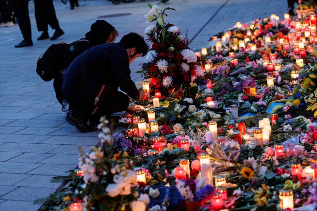 People leave flowers and candles at a makeshift memorial in front of the Paulinum (University Auditorium and St Pauli University Church) in Leipzig, eastern Germany, close to the site where a car ploughed into people on a street, leaving at least two dead and several injured, one day after the incident, on May 5, 2026. A man suspected of ploughing a car into a crowd in the eastern German city of Leipzig, killing two people, recently underwent treatment in a psychiatric hospital, the authorities said on May 5. The German national allegedly drove the vehicle on May 4 at high speed down a main street in the historic centre of the eastern city, leaving two people dead and many others wounded. The 33-year-old suspect was arrested at the scene and officials have said they do not believe he had a political or religious motive. (Photo by Jens SCHLÜTER / AFP)