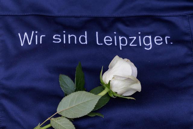 A flowers is pictured nex to the words "We are leipzigers" at a makeshift memorial in front of the Paulinum (University Auditorium and St Pauli University Church) in Leipzig, eastern Germany, close to the site where a car ploughed into people on a street, leaving at least two dead and several injured, one day after the incident, on May 5, 2026. A man suspected of ploughing a car into a crowd in the eastern German city of Leipzig, killing two people, recently underwent treatment in a psychiatric hospital, the authorities said on May 5. The German national allegedly drove the vehicle on May 4 at high speed down a main street in the historic centre of the eastern city, leaving two people dead and many others wounded. The 33-year-old suspect was arrested at the scene and officials have said they do not believe he had a political or religious motive. (Photo by Jens SCHLÜTER / AFP)