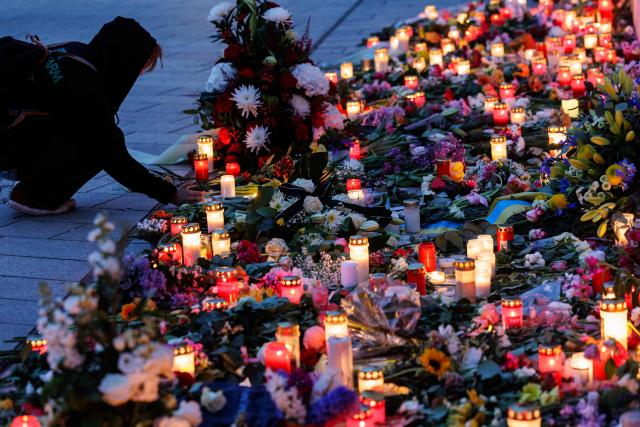 People leave flowers and candles at a makeshift memorial in front of the Paulinum (University Auditorium and St Pauli University Church) in Leipzig, eastern Germany, close to the site where a car ploughed into people on a street, leaving at least two dead and several injured, one day after the incident, on May 5, 2026. A man suspected of ploughing a car into a crowd in the eastern German city of Leipzig, killing two people, recently underwent treatment in a psychiatric hospital, the authorities said on May 5. The German national allegedly drove the vehicle on May 4 at high speed down a main street in the historic centre of the eastern city, leaving two people dead and many others wounded. The 33-year-old suspect was arrested at the scene and officials have said they do not believe he had a political or religious motive. (Photo by Jens SCHLÜTER / AFP)