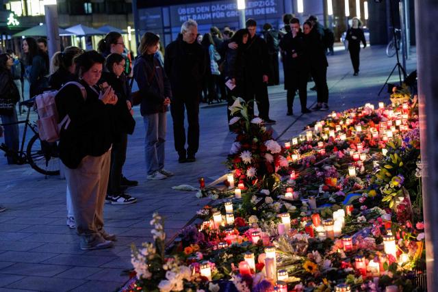 People leave flowers and candles at a makeshift memorial in front of the Paulinum (University Auditorium and St Pauli University Church) in Leipzig, eastern Germany, close to the site where a car ploughed into people on a street, leaving at least two dead and several injured, one day after the incident, on May 5, 2026. A man suspected of ploughing a car into a crowd in the eastern German city of Leipzig, killing two people, recently underwent treatment in a psychiatric hospital, the authorities said on May 5. The German national allegedly drove the vehicle on May 4 at high speed down a main street in the historic centre of the eastern city, leaving two people dead and many others wounded. The 33-year-old suspect was arrested at the scene and officials have said they do not believe he had a political or religious motive. (Photo by Jens SCHLÜTER / AFP)