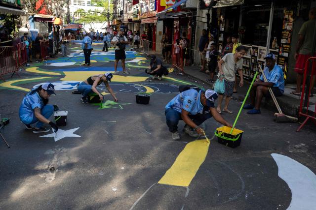 Local artists paint a street ahead of the FIFA World Cup 2026 in the Rocinha favela in Rio de Janeiro, Brazil, on May 5, 2026. (Photo by Pablo PORCIUNCULA / AFP)