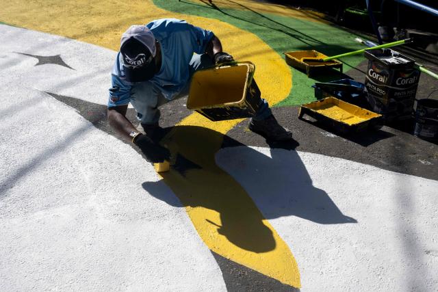 A local artist paints a street ahead of the FIFA World Cup 2026 in the Rocinha favela in Rio de Janeiro, Brazil, on May 5, 2026. (Photo by Pablo PORCIUNCULA / AFP)