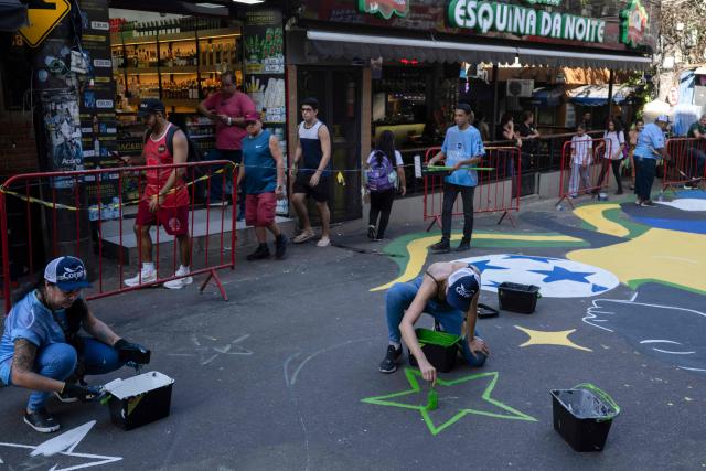 Local artists paint a street ahead of the FIFA World Cup 2026 in the Rocinha favela in Rio de Janeiro, Brazil, on May 5, 2026. (Photo by Pablo PORCIUNCULA / AFP)