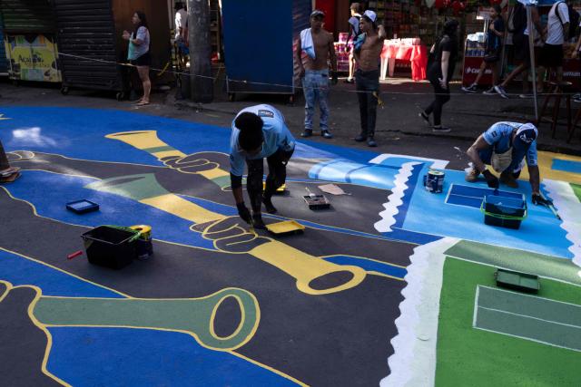 Local artists paint a street ahead of the FIFA World Cup 2026 in the Rocinha favela in Rio de Janeiro, Brazil, on May 5, 2026. (Photo by Pablo PORCIUNCULA / AFP)