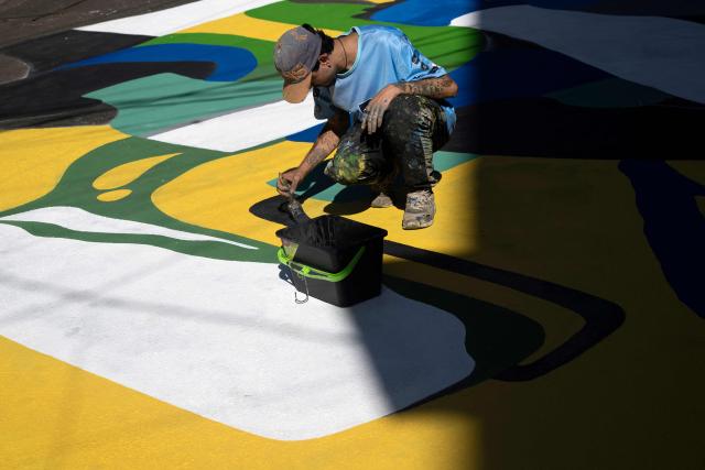 A local artist paints a street ahead of the FIFA World Cup 2026 in the Rocinha favela in Rio de Janeiro, Brazil, on May 5, 2026. (Photo by Pablo PORCIUNCULA / AFP)