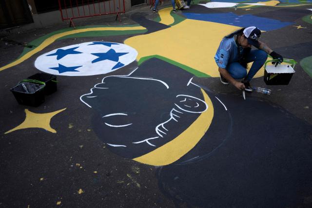 A local artist paints a street ahead of the FIFA World Cup 2026 in the Rocinha favela in Rio de Janeiro, Brazil, on May 5, 2026. (Photo by Pablo PORCIUNCULA / AFP)