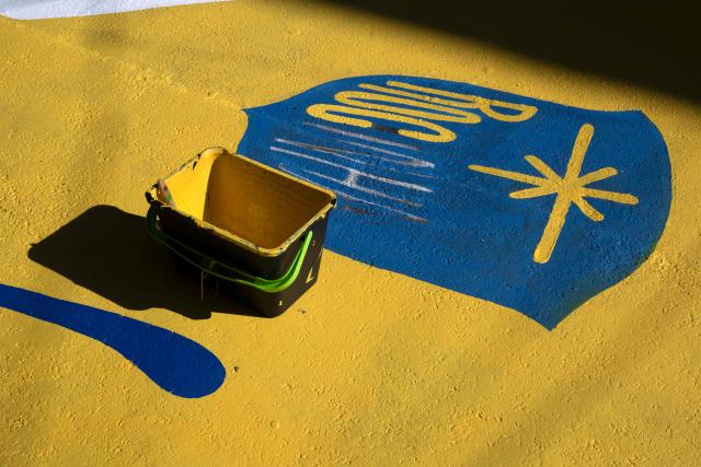 A paint bucket sits on a street painted with World Cup-themed designs ahead of the FIFA World Cup 2026 in the Rocinha favela in Rio de Janeiro, Brazil, on May 5, 2026. (Photo by Pablo PORCIUNCULA / AFP)