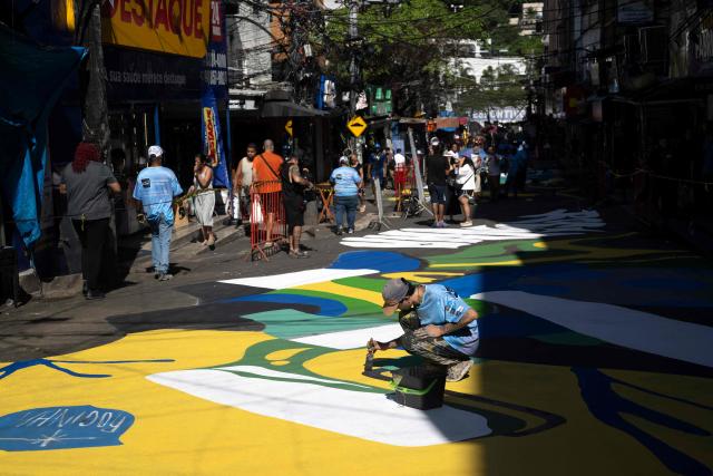 A local artist paints a street ahead of the FIFA World Cup 2026 in the Rocinha favela in Rio de Janeiro, Brazil, on May 5, 2026. (Photo by Pablo PORCIUNCULA / AFP)