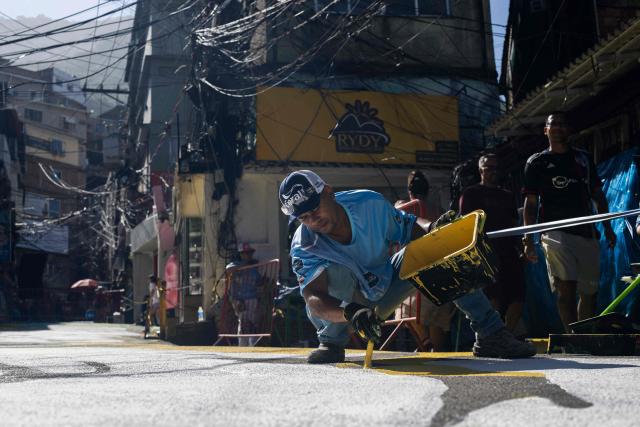 A local artist paints a street ahead of the FIFA World Cup 2026 in the Rocinha favela in Rio de Janeiro, Brazil, on May 5, 2026. (Photo by Pablo PORCIUNCULA / AFP)